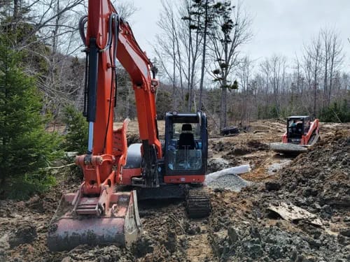 Backhoe And Skid Steer Working In Boggy Soil